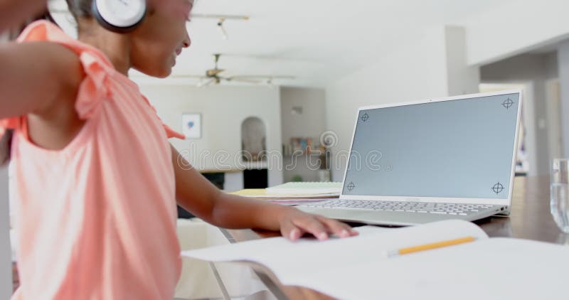 Garota biracial feliz em fones de ouvido que tem aula de espaço no laptop em câmera lenta na tela