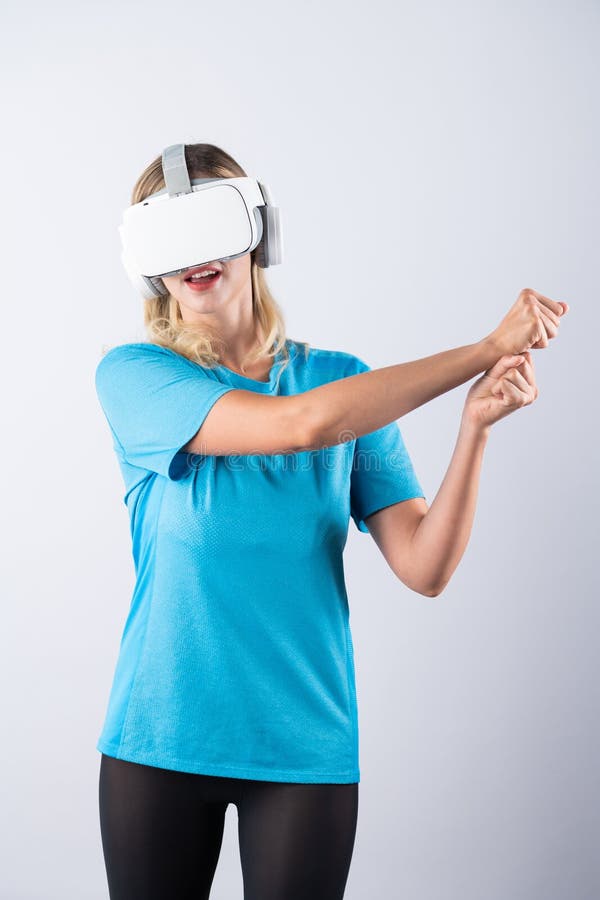 Caucasian girl playing golf and moving gesture by using VR glasses. Happy sport gamer with casual cloth playing game while wearing visual reality headset and standing at pink background. Contraption. Caucasian girl playing golf and moving gesture by using VR glasses. Happy sport gamer with casual cloth playing game while wearing visual reality headset and standing at pink background. Contraption.