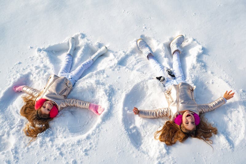 Garota feliz em shows de anjo de neve. Duas garotinhas fazendo anjo de neve enquanto deitado na neve fotografia de stock Garota feliz em shows de anjo de neve. Duas garotinhas fazendo anjo de neve enquanto deitado na neve fotografia de stock