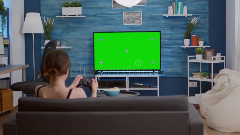 Uma menina sentada no sofá jogando um vídeo na sala de estar em casa. mão  de menina gamer animado segurando o joystick jogando jogo de console usando  um controlador sem fio.