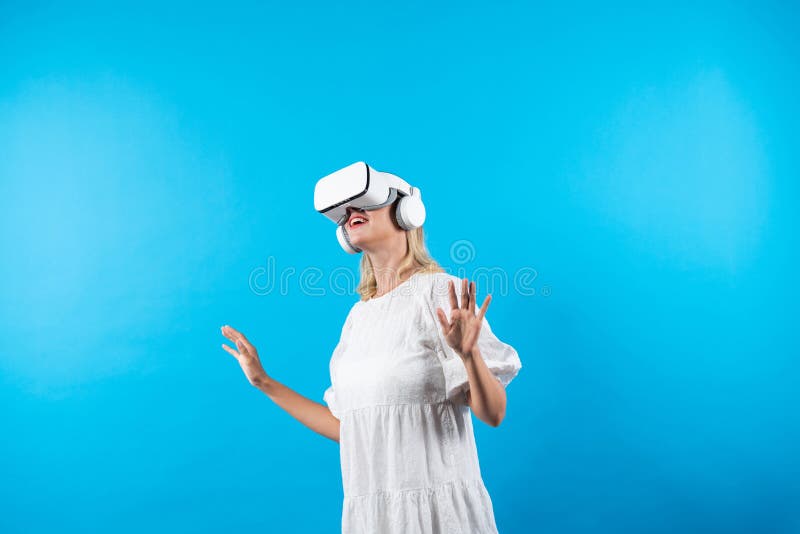 Skilled girl in pajamas excited with metaverse by using VR goggle at background. Caucasian woman surprised while looking around at futuristic view looking though visual reality goggles. Contraption. Skilled girl in pajamas excited with metaverse by using VR goggle at background. Caucasian woman surprised while looking around at futuristic view looking though visual reality goggles. Contraption.