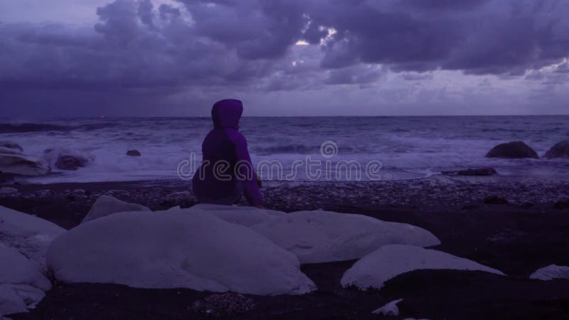 Garota no litoral contra o pano de fundo das ondas de tempestade
