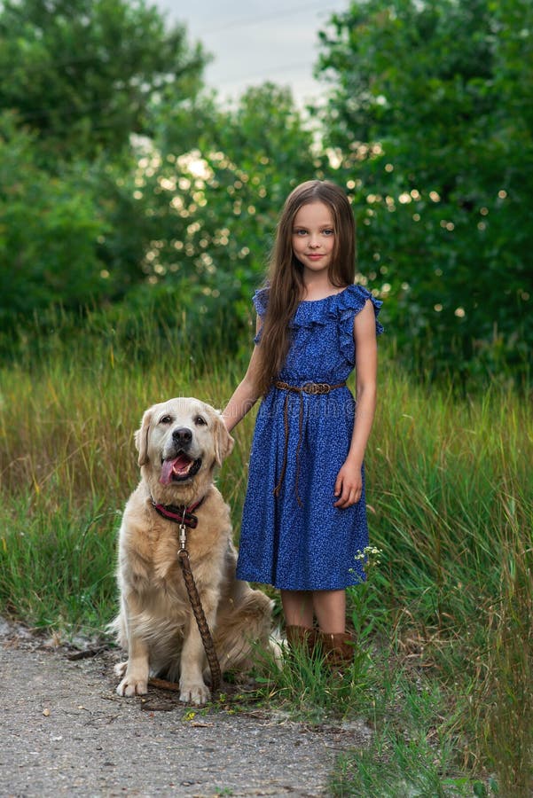 Little girl playing with her big dog outdoors in rural areas in summer. kid with  golden retriever in the summer park. Looking into the camera. Little girl playing with her big dog outdoors in rural areas in summer. kid with  golden retriever in the summer park. Looking into the camera