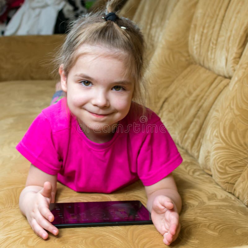 Sorridente menina deitada no sofá confortável, gostando de jogar jogo  online no computador tablet digital. viciado em tecnologia, criança feliz  usando aplicativos engraçados, informações de navegação na web.