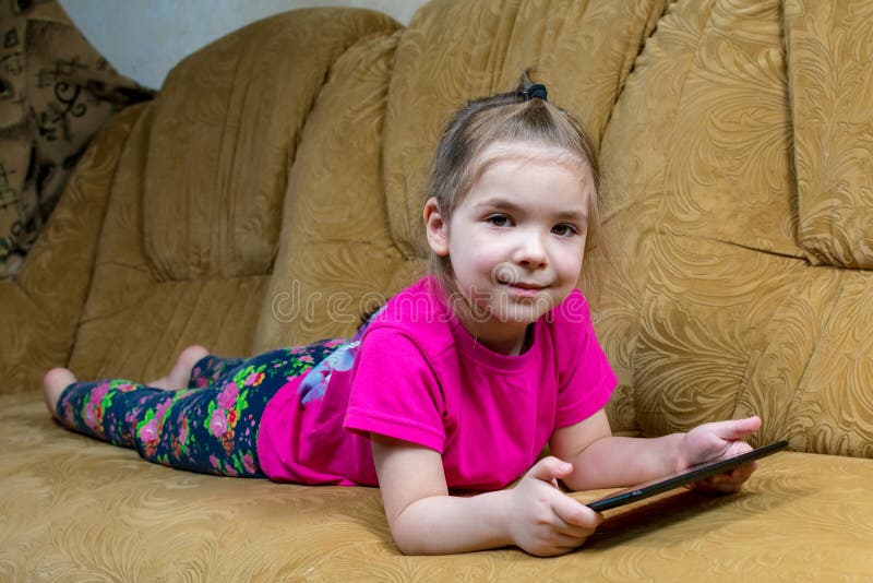 Sorridente menina deitada no sofá confortável, gostando de jogar jogo  online no computador tablet digital. viciado em tecnologia, criança feliz  usando aplicativos engraçados, informações de navegação na web.