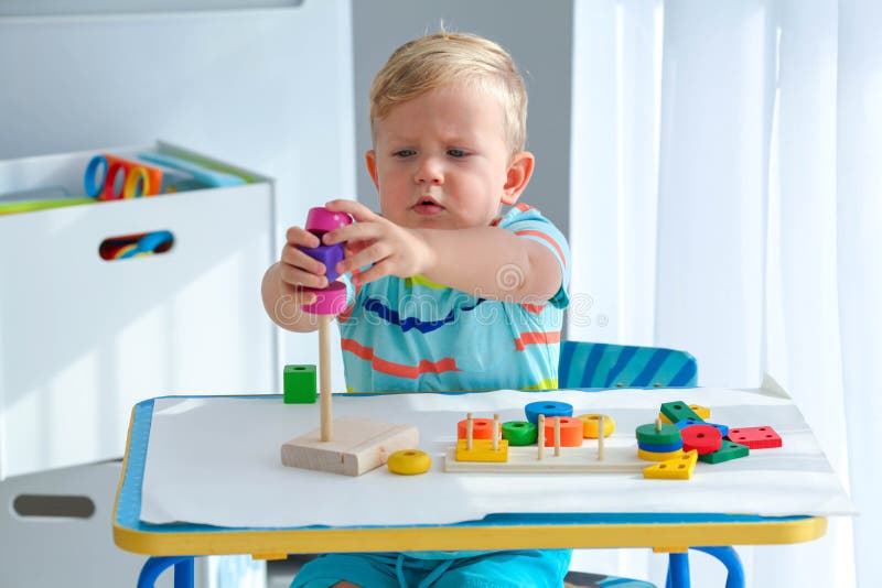 Garotinho De 2 Anos é Tocado Com Uma Pirâmide De Madeira. Brinquedos  Lógicos Educativos Para Crianças. Jogos Montessori Para Crian Foto de Stock  - Imagem de eduque, jogo: 201508416