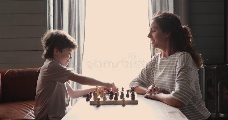 Menino fofo de 5 anos jogando xadrez sozinho em seu quarto em casa