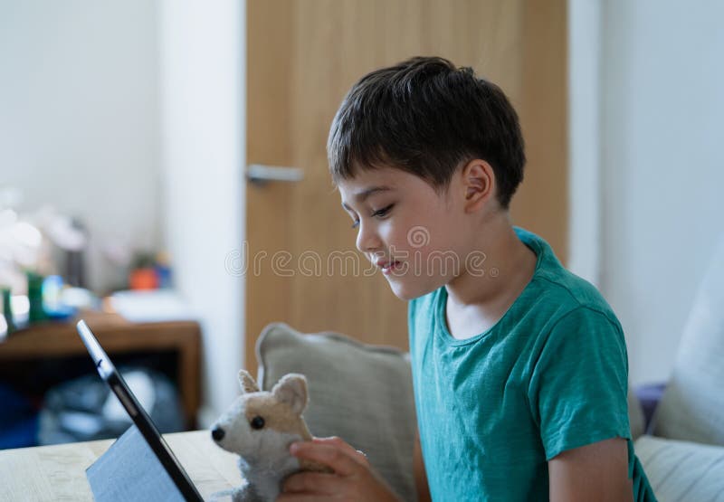 criança jogando jogos online na internet no quarto, retrato de menino  usando tablet digitando ou conversando com amigos de manhã, infância  sentada na cama fazendo lição de casa, criança da escola com