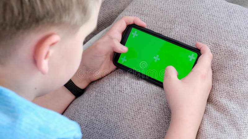 retrato cenimatic menino jogando no celular enquanto espera por comida,  garoto sentado no café enviando texto para amigos, criança jogando jogo  online no telefone. 9711757 Foto de stock no Vecteezy