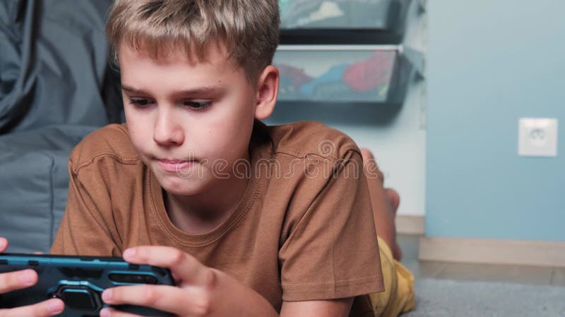 retrato cenimatic menino jogando no celular enquanto espera por comida,  garoto sentado no café enviando texto para amigos, criança jogando jogo  online no telefone. 9711757 Foto de stock no Vecteezy
