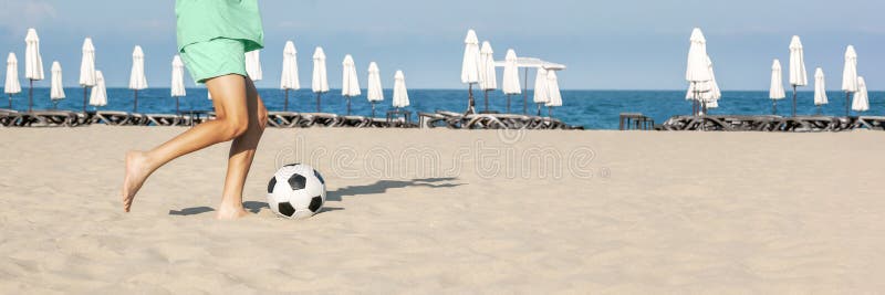 Garoto Joga Bola De Futebol Na Praia Arenosa. Pés Descalços De