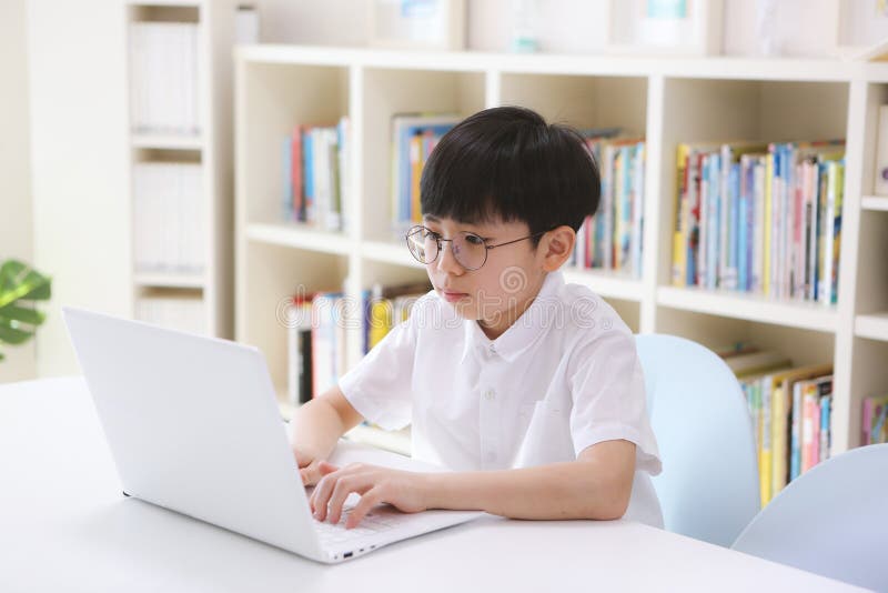 A boy concentrating on his studies while taking video lessons online through the internet on a laptop at home. A boy concentrating on his studies while taking video lessons online through the internet on a laptop at home