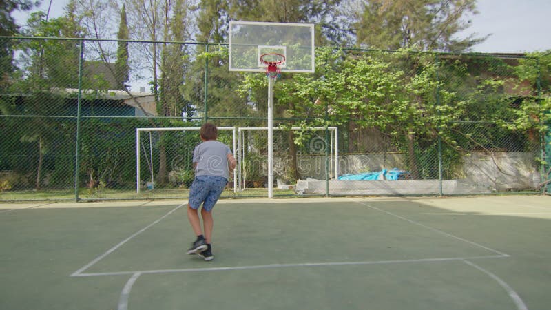 Esportivo com bola para jogar basquete, ouvindo música em fones de ouvido  no parquinho do campo