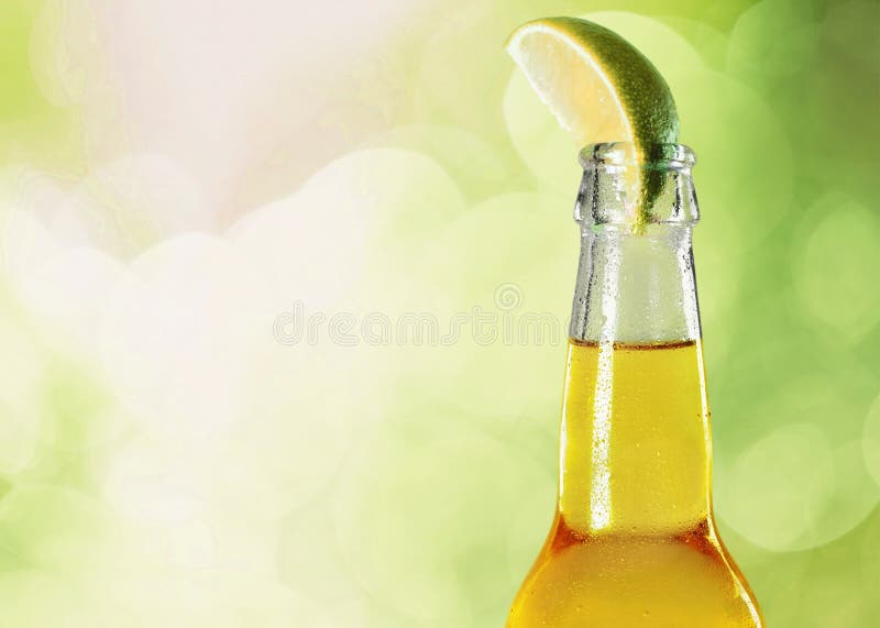 Garrafa da cerveja com cal no fundo borrado foto de stock Garrafa da cerveja com cal no fundo borrado foto de stock