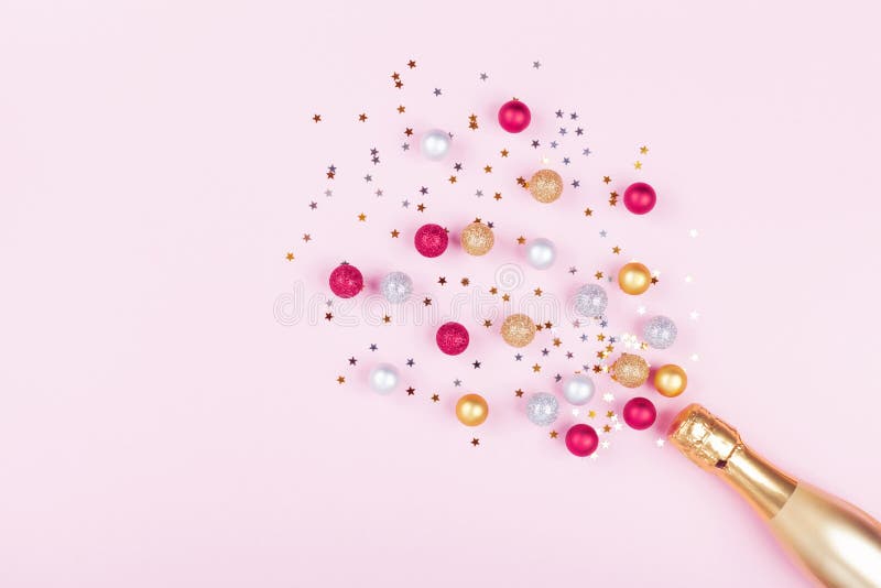 Garrafa de Champagne com estrelas dos confetes e bolas do feriado no fundo cor-de-rosa pastel Teste padrão do Natal estilo liso d fotos de stock Garrafa de Champagne com estrelas dos confetes e bolas do feriado no fundo cor-de-rosa pastel Teste padrão do Natal estilo liso d fotos de stock