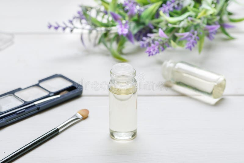 Garrafa de vidro com óleo nele, em artigos cosméticos da composição e em flor da alfazema em uma tabela de madeira branca imagem de stock royalty free Garrafa de vidro com óleo nele, em artigos cosméticos da composição e em flor da alfazema em uma tabela de madeira branca imagem de stock royalty free