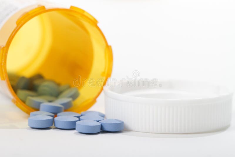 A macro shot of pills spilling out of orange prescription bottle, on white background. A macro shot of pills spilling out of orange prescription bottle, on white background.