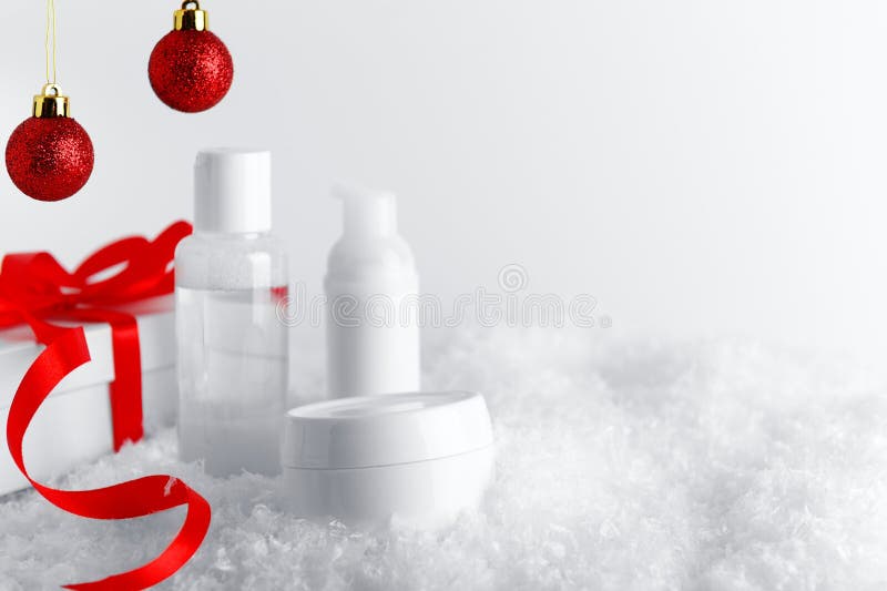 Garrafas de cosméticos Skincare sobre a superfície coberta de neve estilizada Caixa branca de presente com fita vermelha e bolhas imagem de stock royalty free Garrafas de cosméticos Skincare sobre a superfície coberta de neve estilizada Caixa branca de presente com fita vermelha e bolhas imagem de stock royalty free