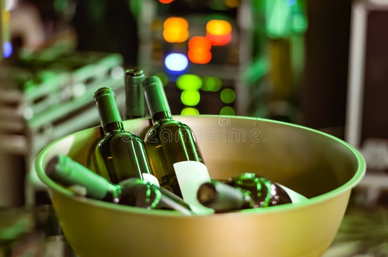 Garrafas do vinho fechadas em uma bacia dourada de aço inoxidável em um partido - evento do ferro em um fundo defocused das luzes imagem de stock royalty free Garrafas do vinho fechadas em uma bacia dourada de aço inoxidável em um partido - evento do ferro em um fundo defocused das luzes imagem de stock royalty free