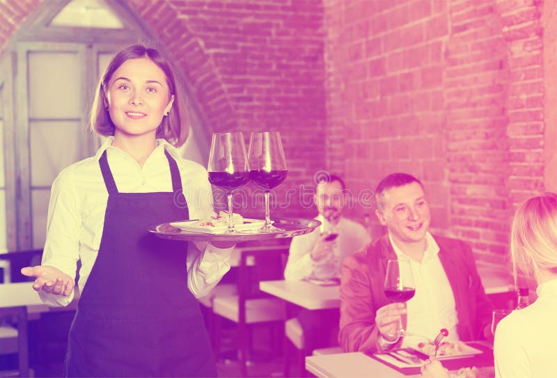 Garçom amigável da mulher que demonstra o restaurante aos visitantes foto de stock Garçom amigável da mulher que demonstra o restaurante aos visitantes foto de stock