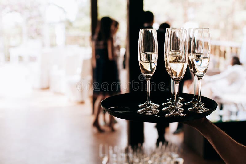 Garçom traz óculos cheios de champanhe em uma bandeja fotos de stock