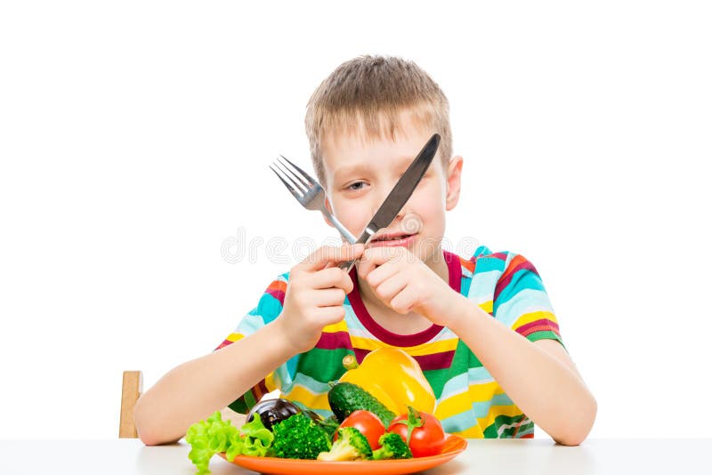 gar?on avec un couteau et une fourchette mangeant les l?gumes crus frais photo libre de droits gar?on avec un couteau et une fourchette mangeant les l?gumes crus frais photo libre de droits