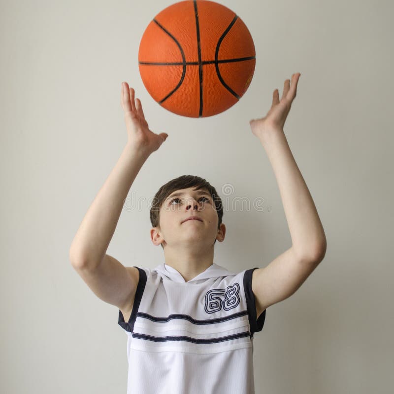 Garçon d'adolescent dans une chemise blanche avec une boule pour le basket-ball photo libre de droits Garçon d'adolescent dans une chemise blanche avec une boule pour le basket-ball photo libre de droits