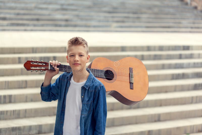 Garçon d'adolescent de portrait avec la guitare acoustique en parc photos stock Garçon d'adolescent de portrait avec la guitare acoustique en parc photos stock