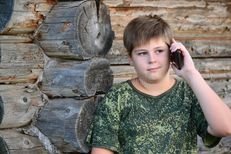 Garçon d'adolescent parlant au téléphone portable se tenant prêt image libre de droits Garçon d'adolescent parlant au téléphone portable se tenant prêt image libre de droits