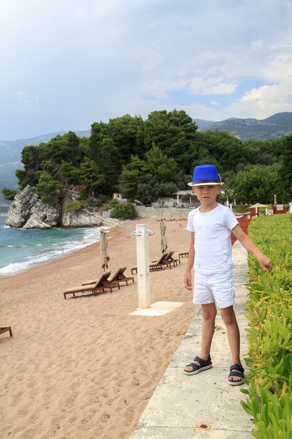 garçon dans les promenades bleues de chapeau sur la plage en parc de Milocher près de Budva photo stock garçon dans les promenades bleues de chapeau sur la plage en parc de Milocher près de Budva photo stock