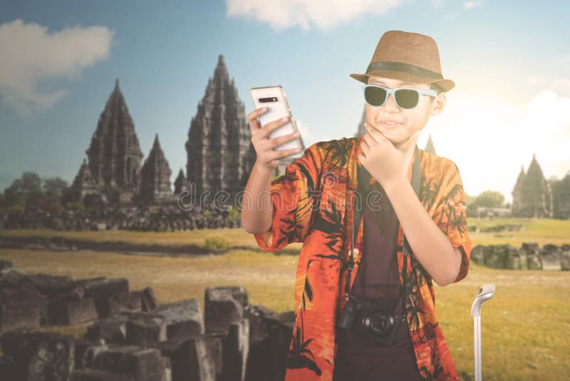 Garçon de la préadolescence prenant la photo près du temple de Prambanan. Vêtements de port d'été de garçon de la préadolescence tout en prenant une photo de selfie près du temple de Prambanan à Yogyakarta, Indonésie