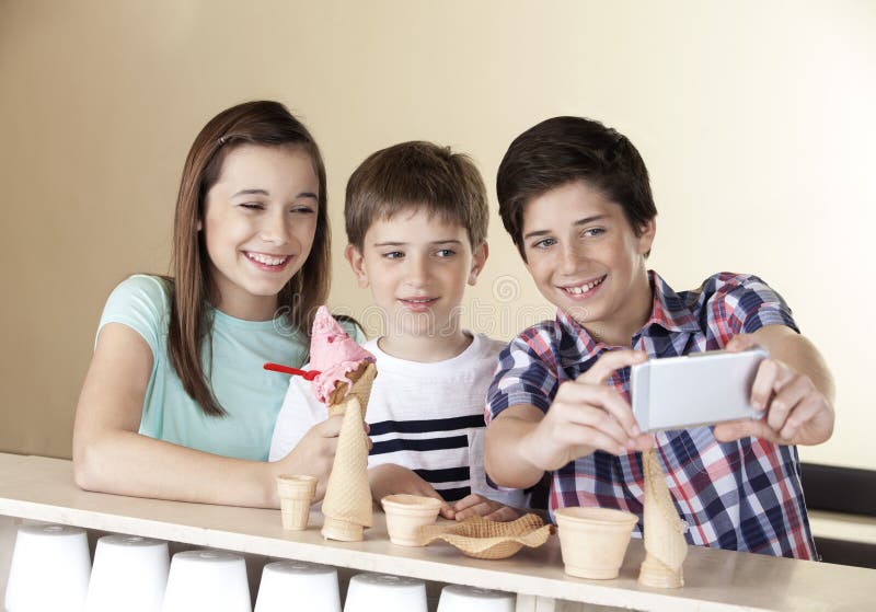 Garçon de la préadolescence prenant Selfie avec des enfants de mêmes parents par le téléphone intelligent photo stock