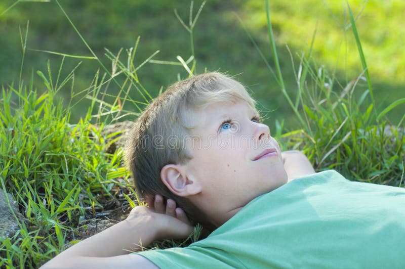 Garçon détendant sur la pelouse d'herbe verte images stock Garçon détendant sur la pelouse d'herbe verte images stock