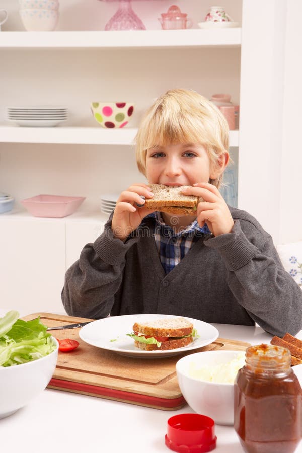 Garçon effectuant le sandwich dans la cuisine image libre de droits Garçon effectuant le sandwich dans la cuisine image libre de droits