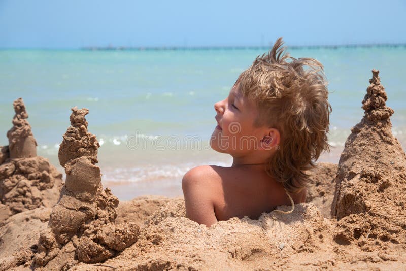 Garçon enterré en sable photographie stock libre de droits Garçon enterré en sable photographie stock libre de droits