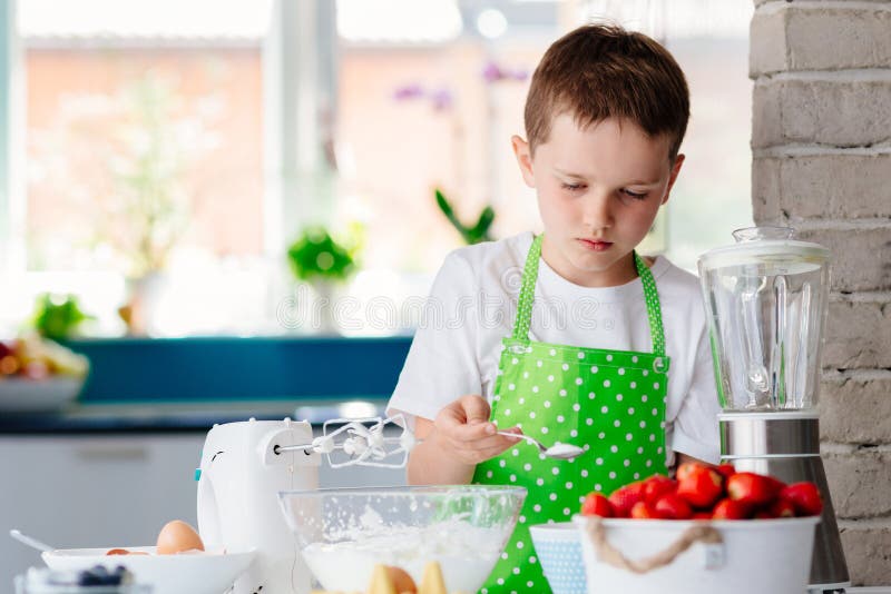 Garçon heureux d'enfant ajoutant le sucre à la cuvette et préparant un gâteau images libres de droits Garçon heureux d'enfant ajoutant le sucre à la cuvette et préparant un gâteau images libres de droits