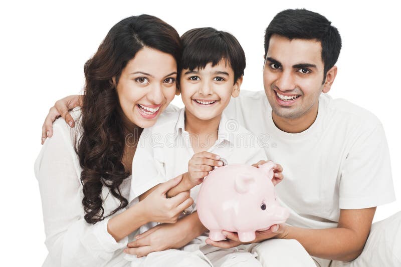Garçon mettant la pièce de monnaie à une tirelire avec son sourire de parents image libre de droits Garçon mettant la pièce de monnaie à une tirelire avec son sourire de parents image libre de droits