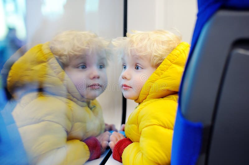 Garçon mignon d'enfant en bas âge regardant la fenêtre de train dehors, tandis qu'il se déplaçant image libre de droits Garçon mignon d'enfant en bas âge regardant la fenêtre de train dehors, tandis qu'il se déplaçant image libre de droits