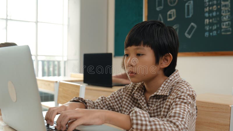 Garçon travaillant sur son ordinateur portable tout en apprenant à coder l'invite en classe. pédagogie. image stock