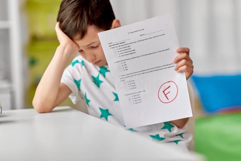 Children, education and learning concept - sad student boy with failed school test at home. Children, education and learning concept - sad student boy with failed school test at home