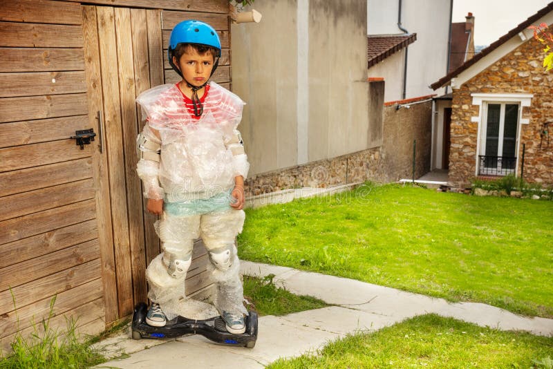 Sad little child kid ride hoverboard and overprotective mother keeping a boy in bubble wrap about super safe. Sad little child kid ride hoverboard and overprotective mother keeping a boy in bubble wrap about super safe