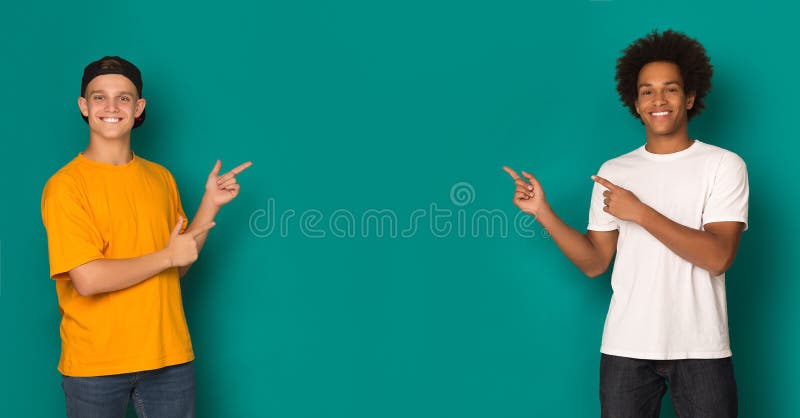 Friendly teen boys pointing on copy space over blue background. Friendly teen boys pointing on copy space over blue background