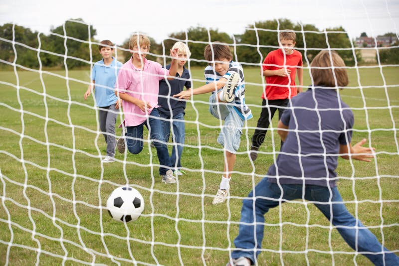 Garçons jouant au football en stationnement photographie stock libre de droits Garçons jouant au football en stationnement photographie stock libre de droits