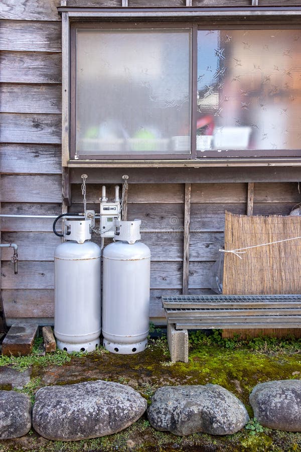 Gas bottles standing outside wall near window of house for heating and cooking