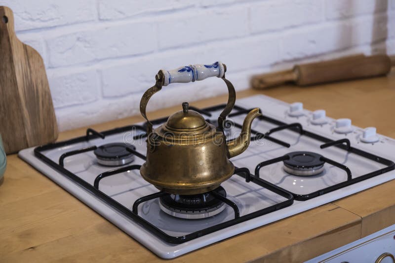 On the Gas Stove is a Copper Kettle with a Beautiful Handle Stock Photo