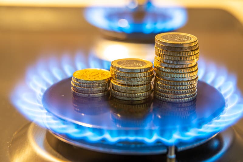 Gas cooking stove on, with coins. Gas cost.