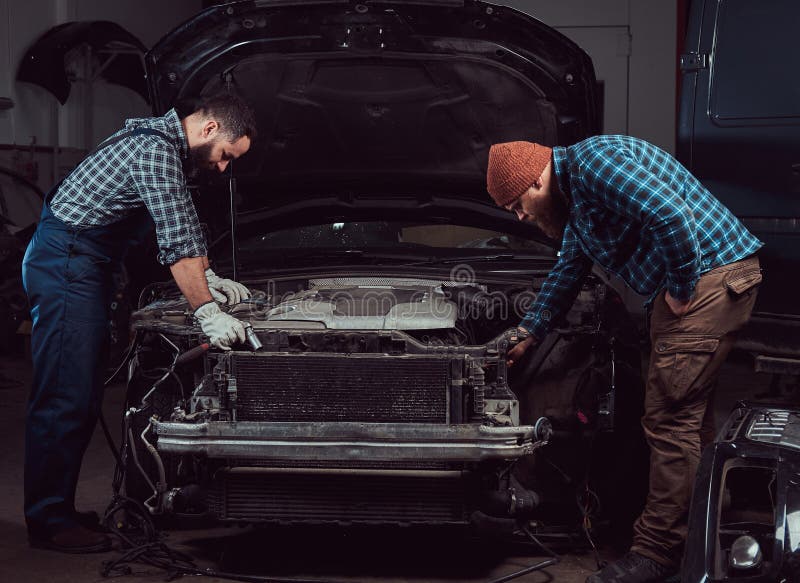 Gasolinera Dos mecánicos brutales barbudos que reparan un coche en el garaje fotos de archivo libres de regalías Gasolinera Dos mecánicos brutales barbudos que reparan un coche en el garaje fotos de archivo libres de regalías
