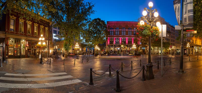 Vancouver, British Columbia / Canada - July 3, 2018: Gastown district during blue hour. `Gassy Jack` statue on the square. Several people sitting in the outdoor areas of the restaurants. Vancouver, British Columbia / Canada - July 3, 2018: Gastown district during blue hour. `Gassy Jack` statue on the square. Several people sitting in the outdoor areas of the restaurants