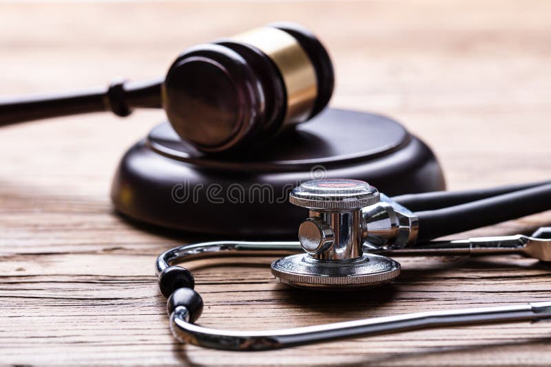 Close-up Of Stethoscope And Gavel Over Wooden Desk. Close-up Of Stethoscope And Gavel Over Wooden Desk