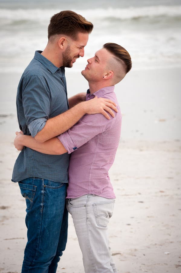 Gay men embracing on a beach.